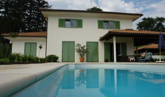 Haus neben einem Pool mit grünen Klappläden