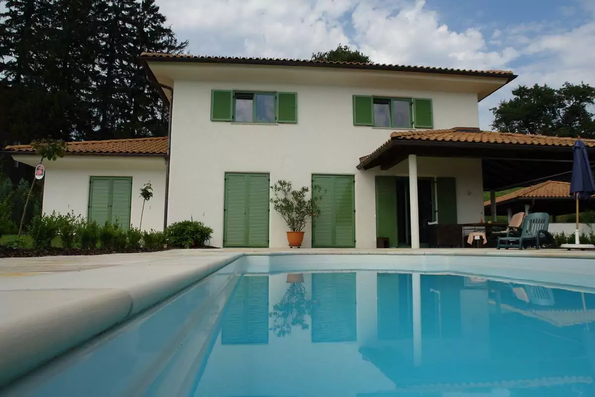 Haus neben einem Pool mit grünen Klappläden