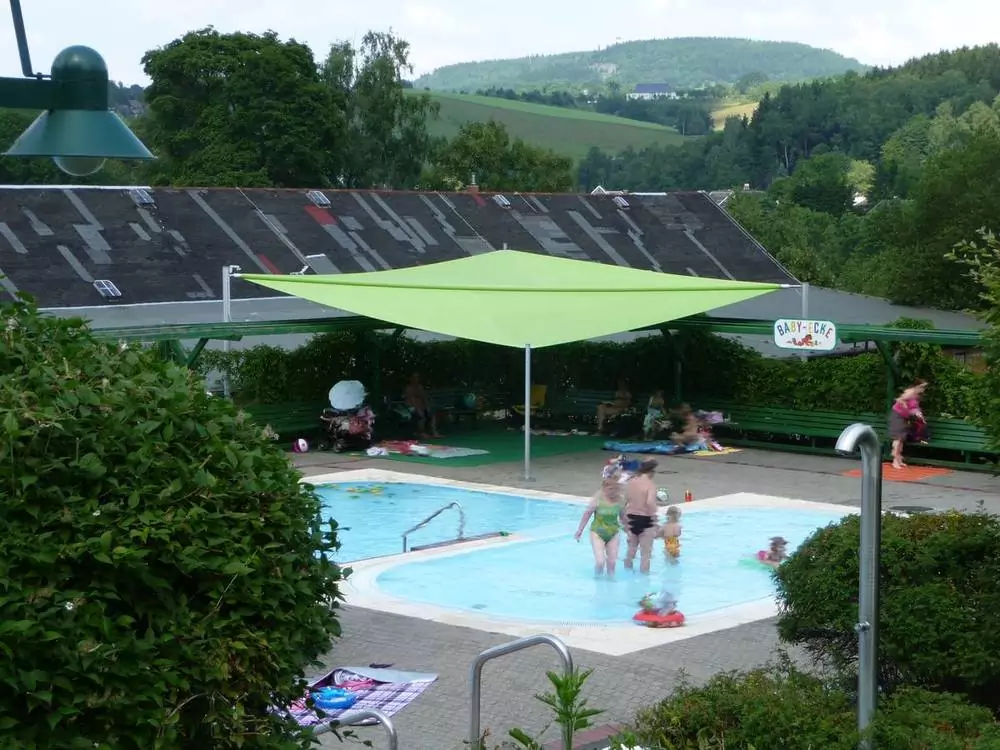 Grünes Sonnensegel neben Kinderbecken im Freibad