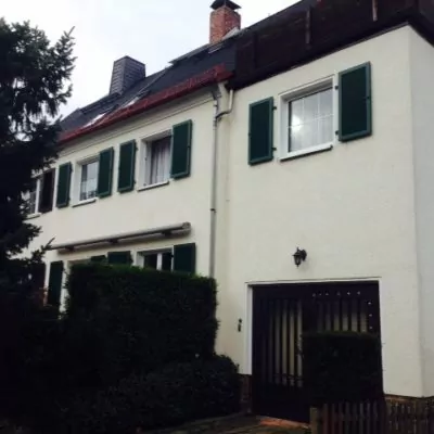 Dunkelgrüne Klappläden an einem Haus mit heller Fassade